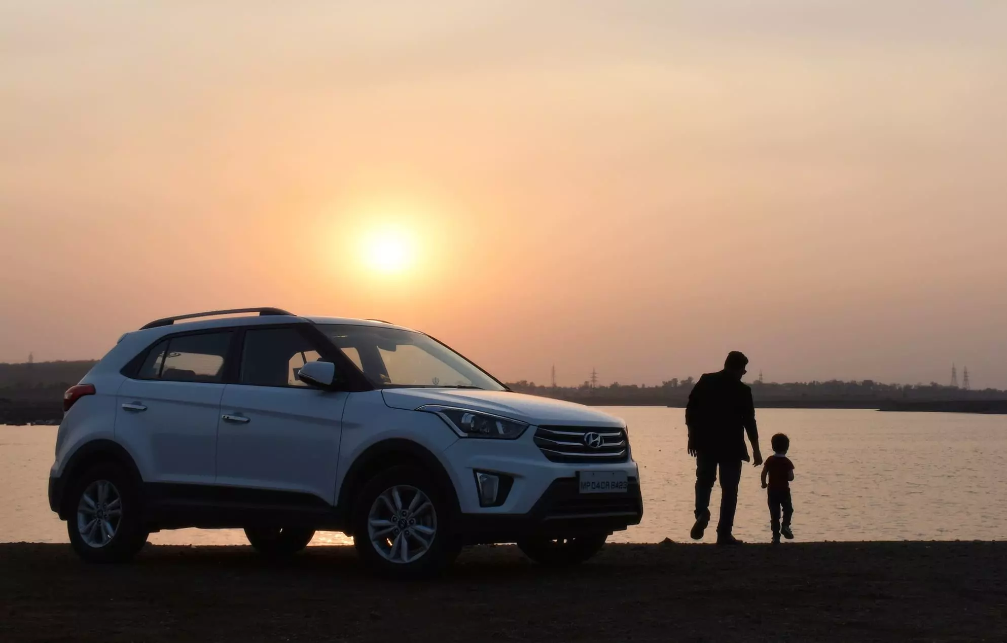 Photo montrant un véhicule ainsi qu'un père et son fils devant un coucher de soleil.